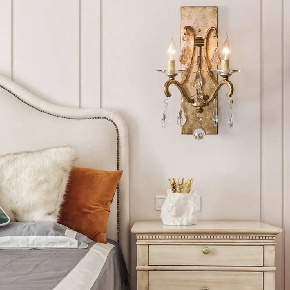 Antique gold-finished industrial rust iron wall sconce with crystal droplets and e12 candle-style bulbs for bedroom use