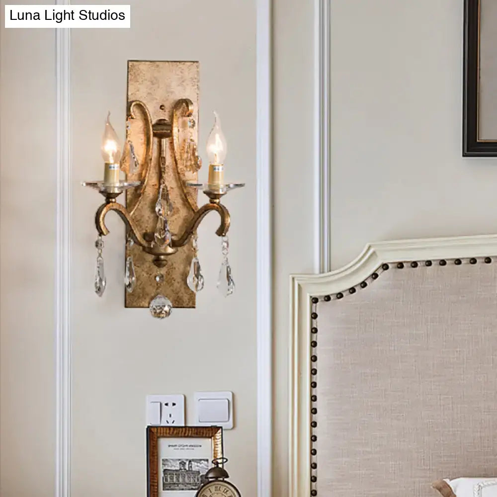Antique gold-finished industrial rust iron wall sconce with crystal droplets and two e12 candle-style bulbs for bedroom lighting
