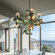 A modern industrial island pendant with smoke gray glass globes and a decorative green vine wreath hanging light