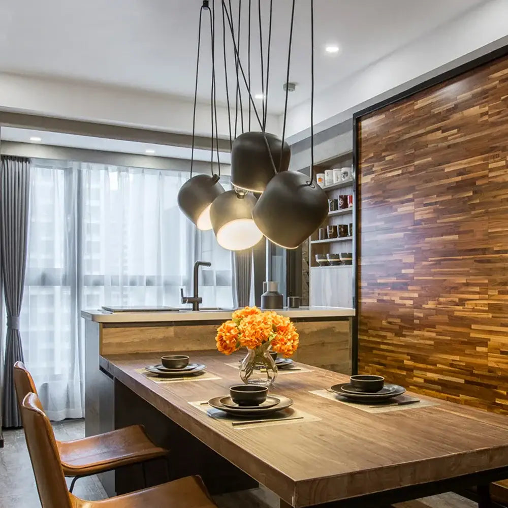 Modern black matte pendant lamp with rounded overlapping shades hanging above wooden dining table decorbites industrial spider pendant