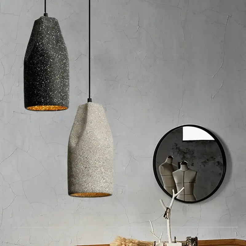 Two textured concrete pendant chandelier lights in speckled gray and beige with gold interiors for decorbites industrial style