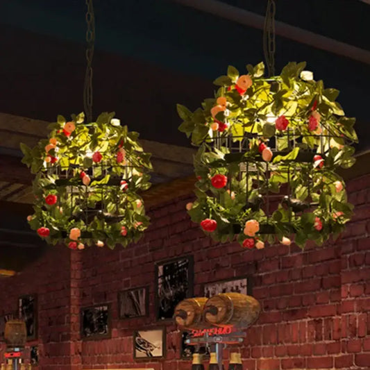 Two spherical hanging lanterns with black metal frames featuring artificial green leaves and red and peach flowers in decorbites industrial style rose chandelier