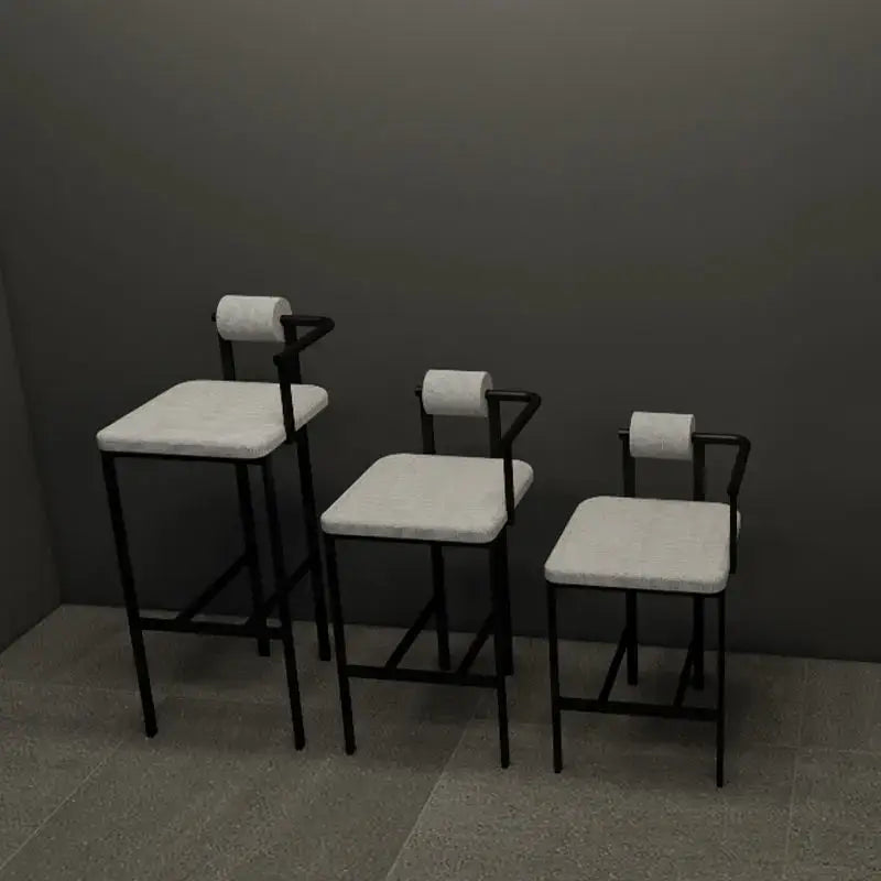 Three minimalist industrial style bar chairs with black metal frames light gray upholstery and toilet paper roll backrests
