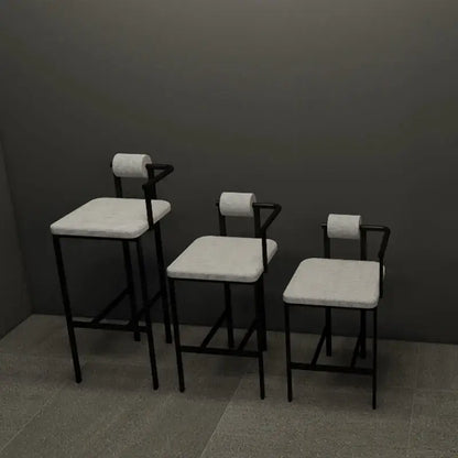 Three minimalist industrial style bar chairs with black metal frames light gray upholstery and toilet paper roll backrests