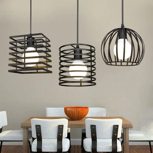 Three black metal pendant lights with cage designs hang above a dining table in a decorbites industrial vintage led set