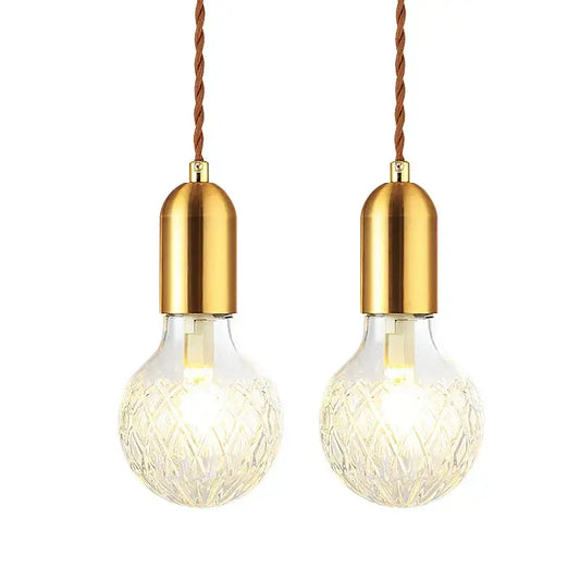 Two elegant brass-finished industrial vintage pendant lights with faceted glass globes and twisted brown cords decorbites