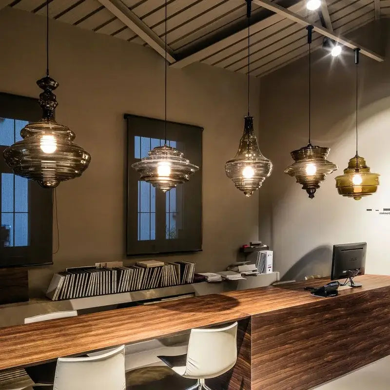 Five amber and clear industrial vintage glass pendant lamps with layered designs illuminating a dining room decorbites setting
