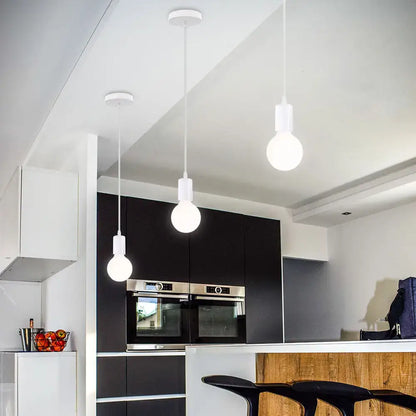 Three minimalist white metal cage pendant lights with exposed bulbs decorate an industrial vintage loft kitchen