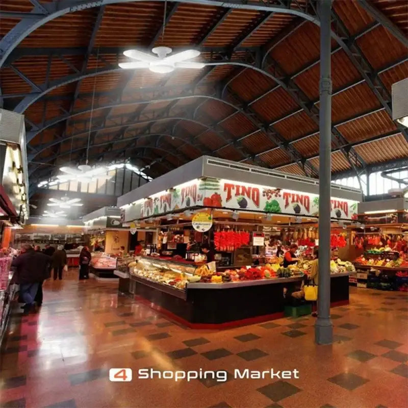 Industrial white deformable led ceiling light with four wings illuminating a bustling indoor market with arched ceilings