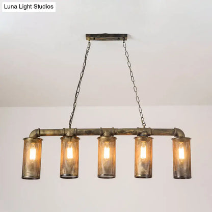 Industrial-style wrought iron pendant light with five amber glass cylinders and 110v-120v bulb base mounted on rustic brass frame
