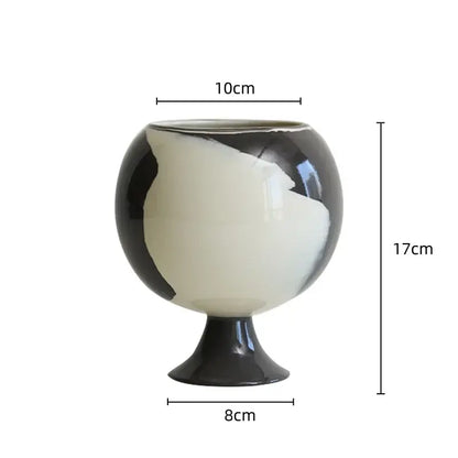 A glossy black and white ceramic irregular grain spherical vase with an asymmetrical body for living room decor