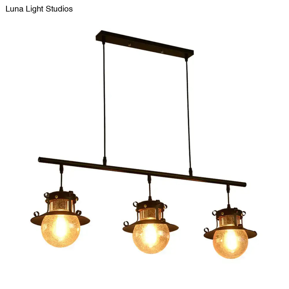 Industrial-style decorbites three-light island pendant with black metal frame and warm amber flared shade globes