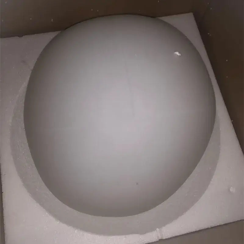 A smooth matte gray spherical decorbites gregg pendant lamp resting on a white foam pad for kitchen lighting