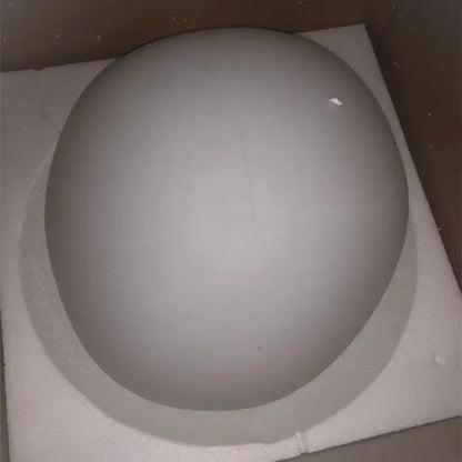 A smooth matte gray spherical decorbites gregg pendant lamp resting on a white foam pad for kitchen lighting