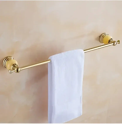Gold-colored towel rack with ornate rounded ends and white towel in jade gold bathroom accessories set with amber marble
