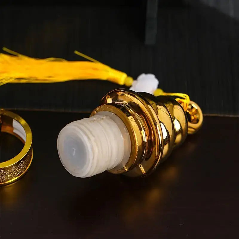 Golden ornate ceramic wine bottle with white frosted cap and yellow tassel used as dining room decor