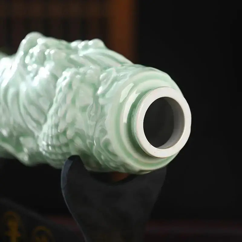 A delicate celadon-green ceramic wine bottle with intricate swirling relief patterns and a glossy finish for dining room decor