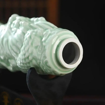 A delicate celadon-green ceramic wine bottle with intricate swirling relief patterns and a glossy finish for dining room decor