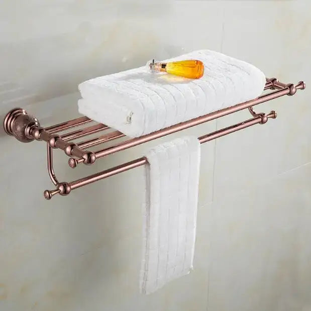 Rose gold double-tier metal towel rack with ornate spherical finials holding white towels from jade rose gold bathroom set