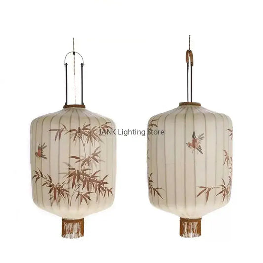 Cream-colored Japanese bamboo leaf pattern paper lantern with brown bird illustrations and woven fringe pendant light