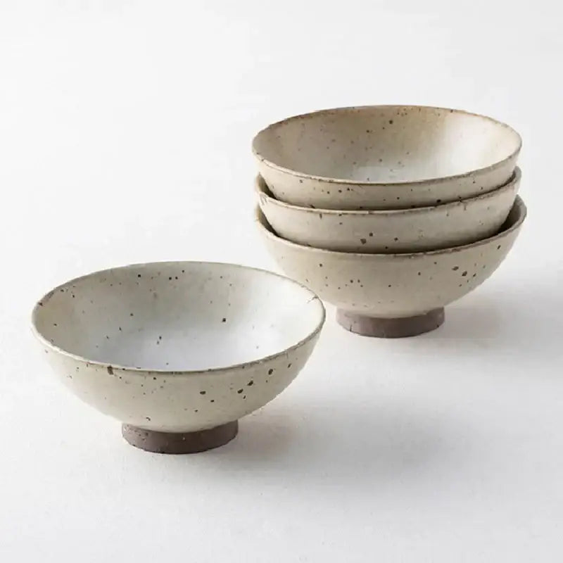 Set of four beige and brown handmade ceramic rice bowls with speckled glaze and footed bases for dining use