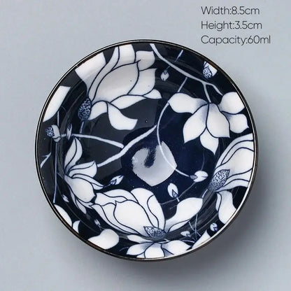 A small round decorbites ceramic kung fu tea bowl with glossy black glaze and delicate white floral patterns