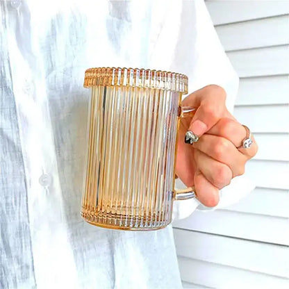 A translucent amber glass coffee cup with vertical ridges and handle held in hand from a Japanese ribbed glass coffee cup set