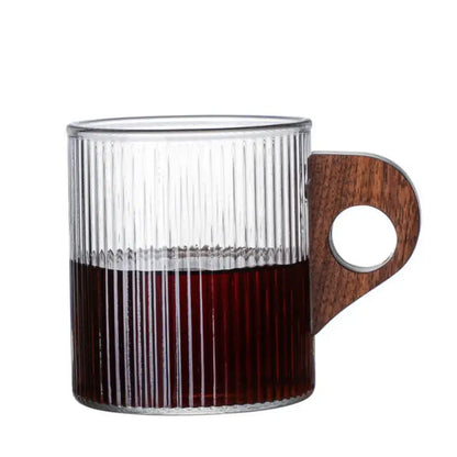 Clear glass coffee mug with vertical ridges and dark brown wooden handle filled with deep red liquid