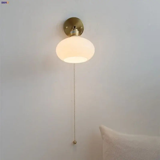 A japanese style led wall sconce with a warm frosted white glass globe and brass finish decorbites pull chain light