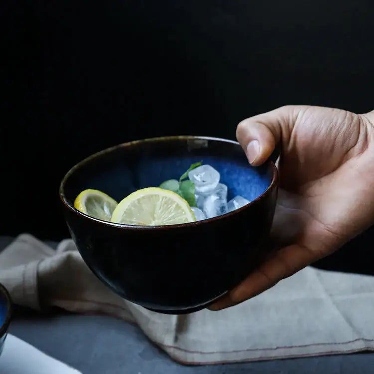 A deep blue ceramic salad bowl set with a dark rustic rim holds lemon slices and ice cubes for dining decorbites ceramic salad