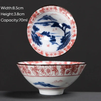A delicate white ceramic kung fu tea cup with blue and red hand-painted cherry blossom landscape decorbites blue design