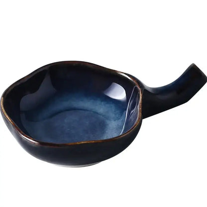 A glossy dark blue ceramic japanese style retro sauce dish with rustic finish and integrated handle for kitchen use