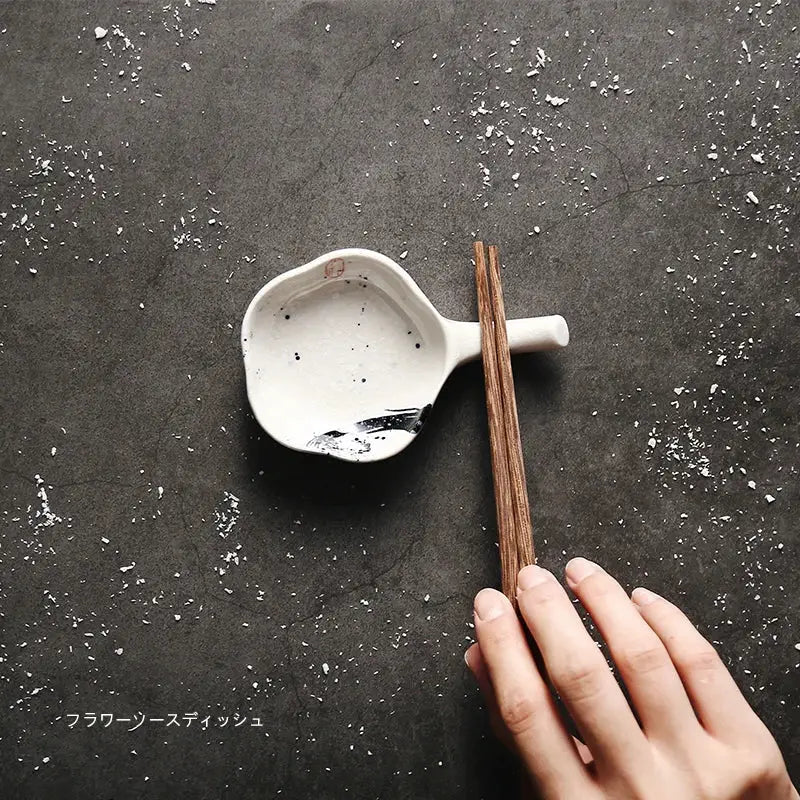 White ceramic chopstick rest with black speckles and brushstroke holding wooden chopsticks decorbites japanese style retro