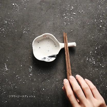 White ceramic chopstick rest with black speckles and brushstroke holding wooden chopsticks decorbites japanese style retro