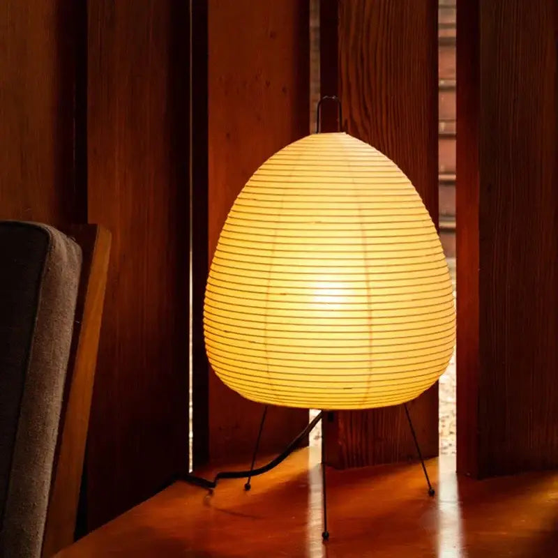 Warmly glowing japanese style rice paper desk lamp with egg-shaped shade and minimalist black metal stand for decorbites bedroom lighting