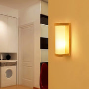 Japanese style wall sconce lamp with warm-toned wooden frame and frosted white glass diffuser for bedroom lighting