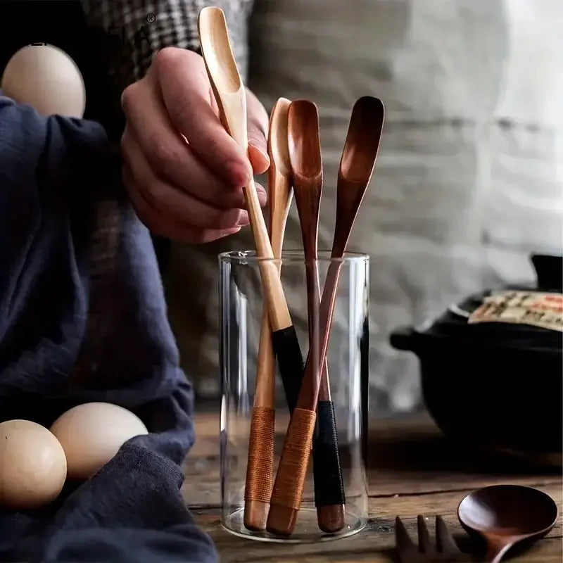 Japanese style wooden spoon set with natural and dark wood handles wrapped in black and brown cord grips in glass jar