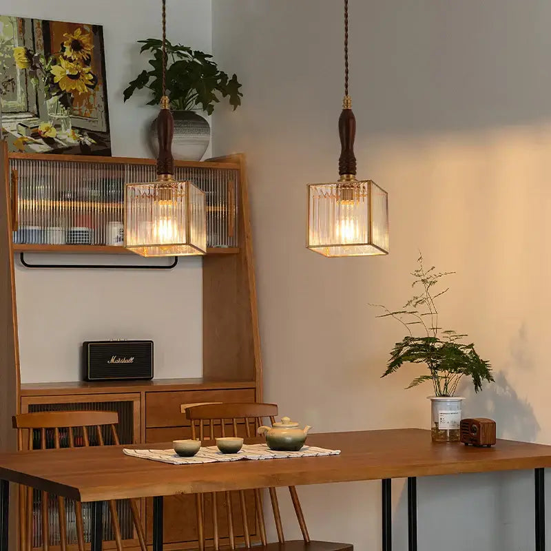 Two warm-toned japanese vintage brass and wood glass led pendant lamps with clear shades hang above a dining table