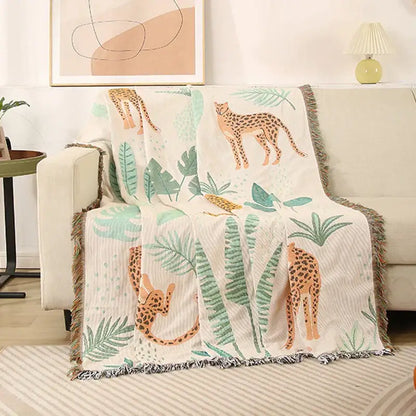 Cozy cream-colored leopard print throw blanket with orange cheetahs and green leaves, fringed edges for decorbites leopard print decor