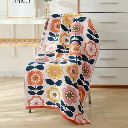 A soft white cotton gauze bath towel with vibrant orange pink yellow and navy floral pattern from decorbites kids cute cats collection