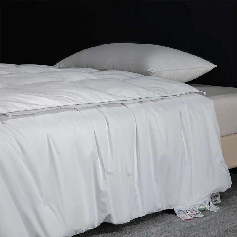 King size white quilted comforter with goose down silk filling smooth shiny fabric subtle stitching for luxury bedroom