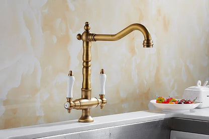 Antique brass kitchen faucet with white ceramic handles and curved spout single hole swivel kitchen faucet
