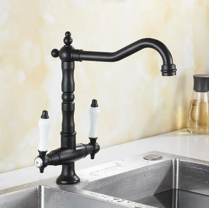 Black matte finished single hole kitchen faucet with white ceramic handles and curved spout mounted on stainless steel sink