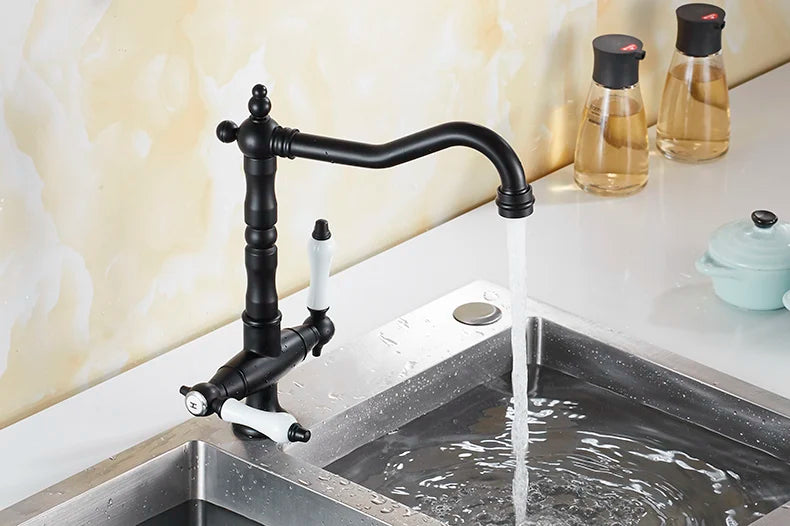 Black matte single hole kitchen faucet with white ceramic handles and curved spout over stainless steel sink