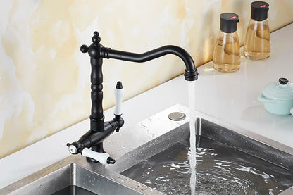 Black matte single hole kitchen faucet with white ceramic handles and curved spout over stainless steel sink