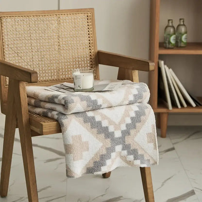 A soft plush knitted geometric quilt blanket in cream gray with a beige gray white pattern for living room decor