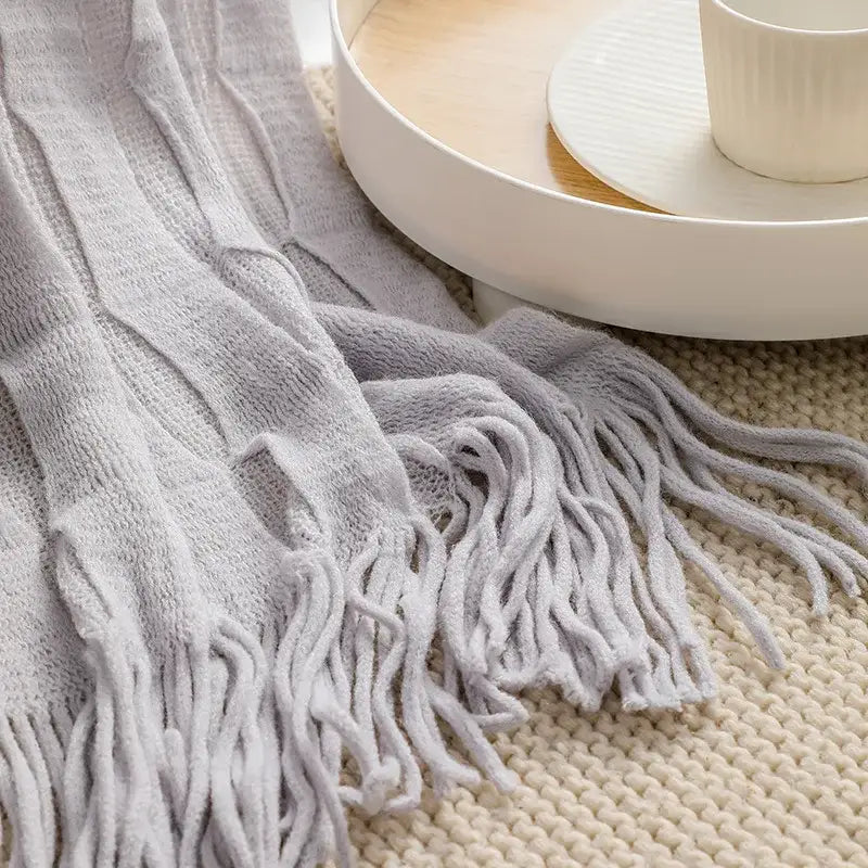 A soft light gray decorbites knitted geometric throw blanket with textured weave and long fluffy fringe for bedroom decor