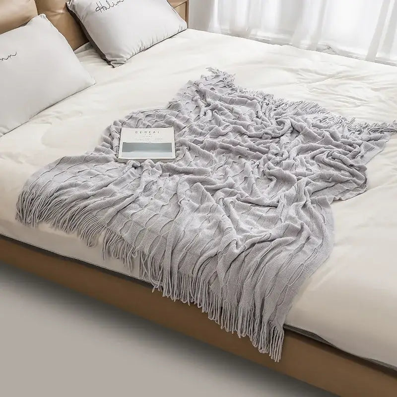 A soft light gray decorbites knitted geometric throw blanket with textured pastel softness and long fringe edges