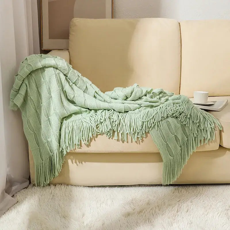 A soft mint green decorbites knitted geometric throw blanket with cable knit pattern and long fringe for bedroom decor