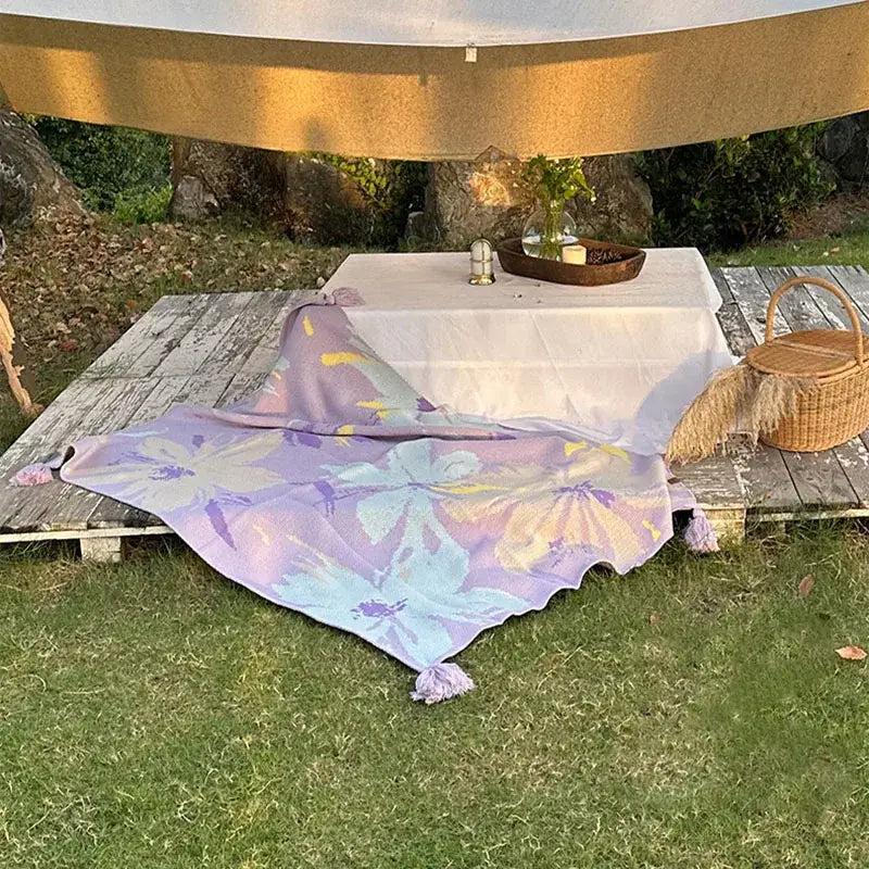 Lavender floral cozy knit blanket with tassels draped on a wooden deck decorbites cozy knit living room throw